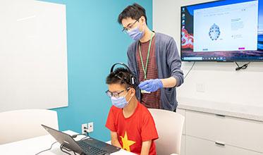 A technician trying a brain reading machine on a kid