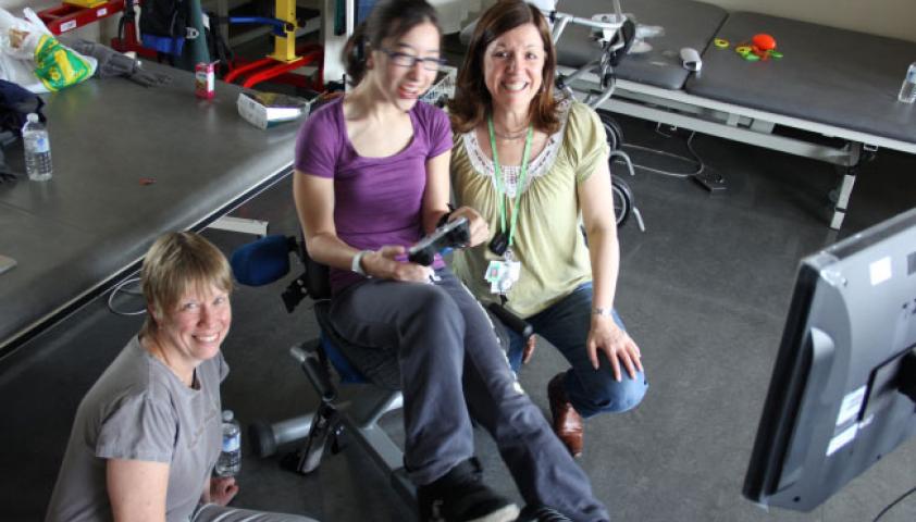 Two female scientists with a young girl using the Exergame bike