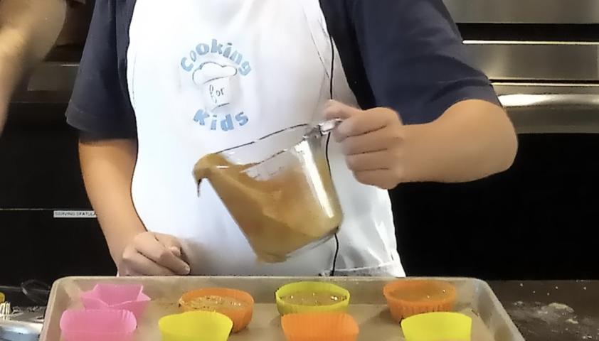 Cooking for kids apron and arm pouring batter