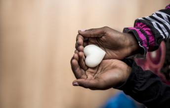 Hands hold a white heart shaped object