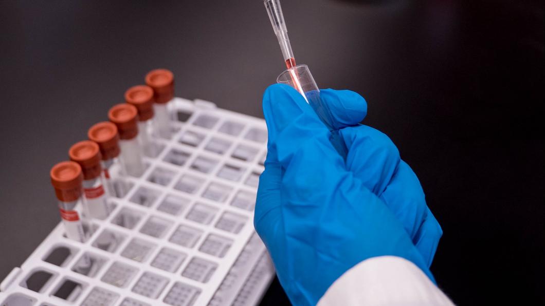 Picture of scientist's hand holding a test tube in a lab