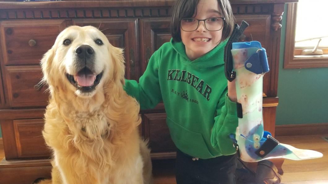 Lexi posing with her dog Cooper as she holds up her AFOs.