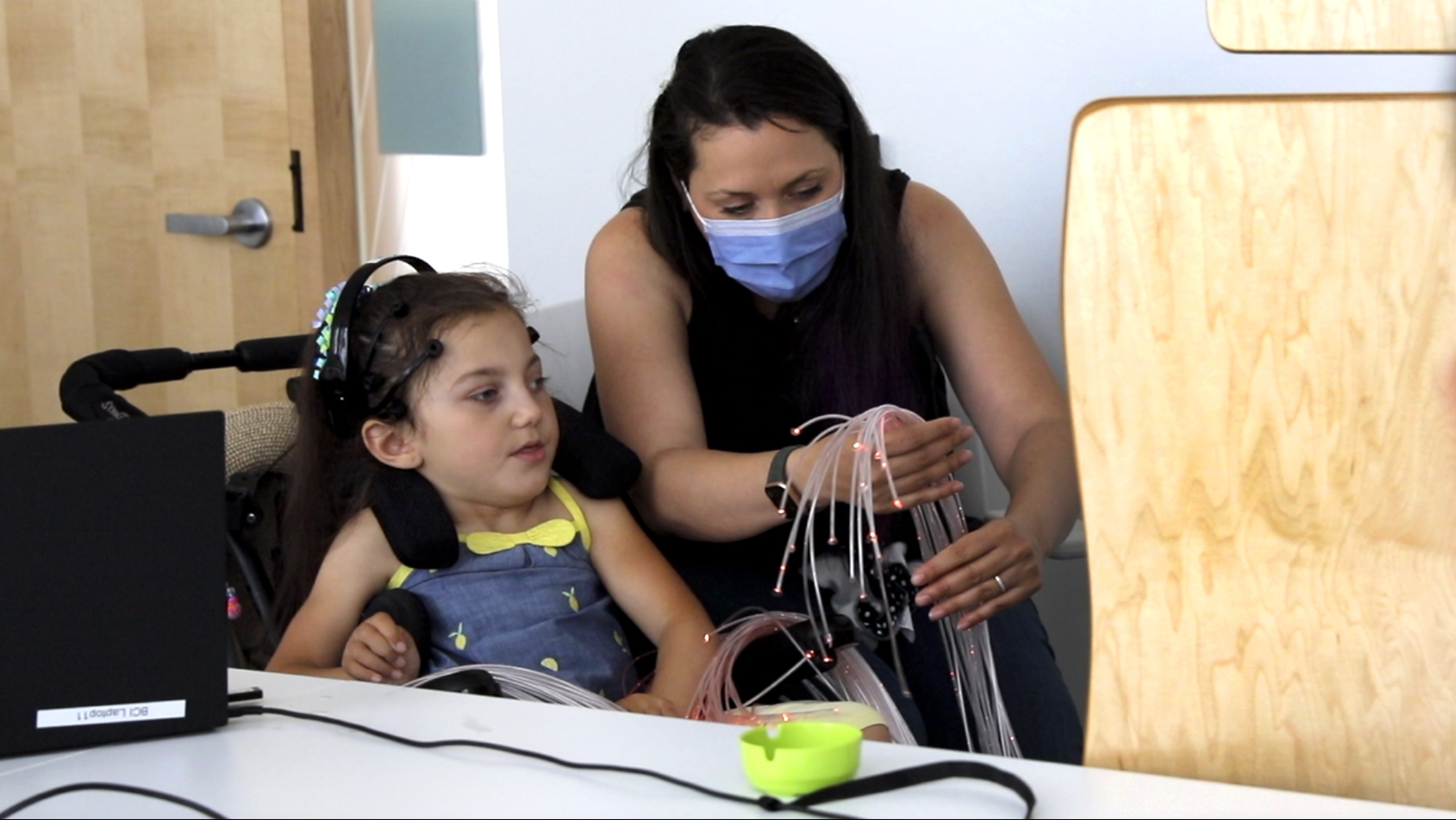 A woman holding some optical fiber wires and connecting to a brain scanning machine