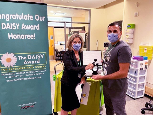 Irene Andress, vice president, programs and services, chief nursing executive, presenting the DAISY Award to Jorge Santos, RN