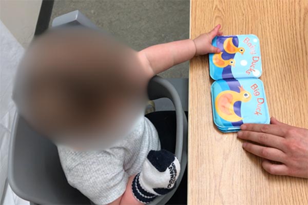 Place a board book in front of infant, show infant how to flip each page with their helper hand.  Lift the page slightly to help infant get started. You could create a small book with cardboard or diaper wipe containers fastened to cardboard.