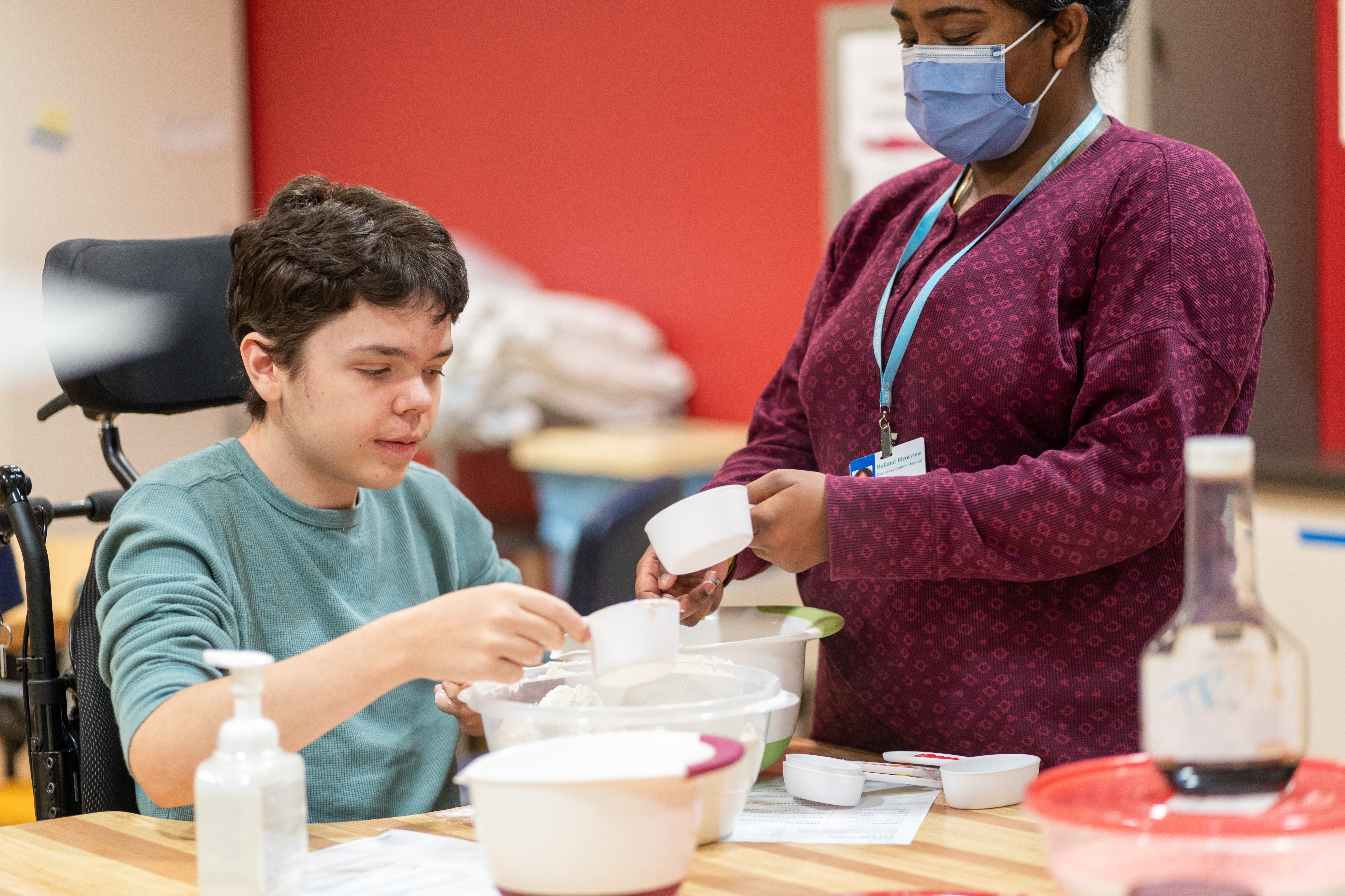 A child who uses a wheelchair bakes with a volunteer.