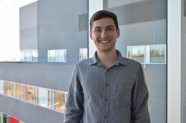 Headshot of Josh Shore smiling with a window overlooking Holland Bloorview as a background