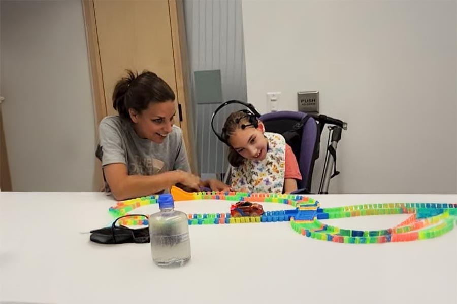 An adult is assisting a child on wheelchair to play a game