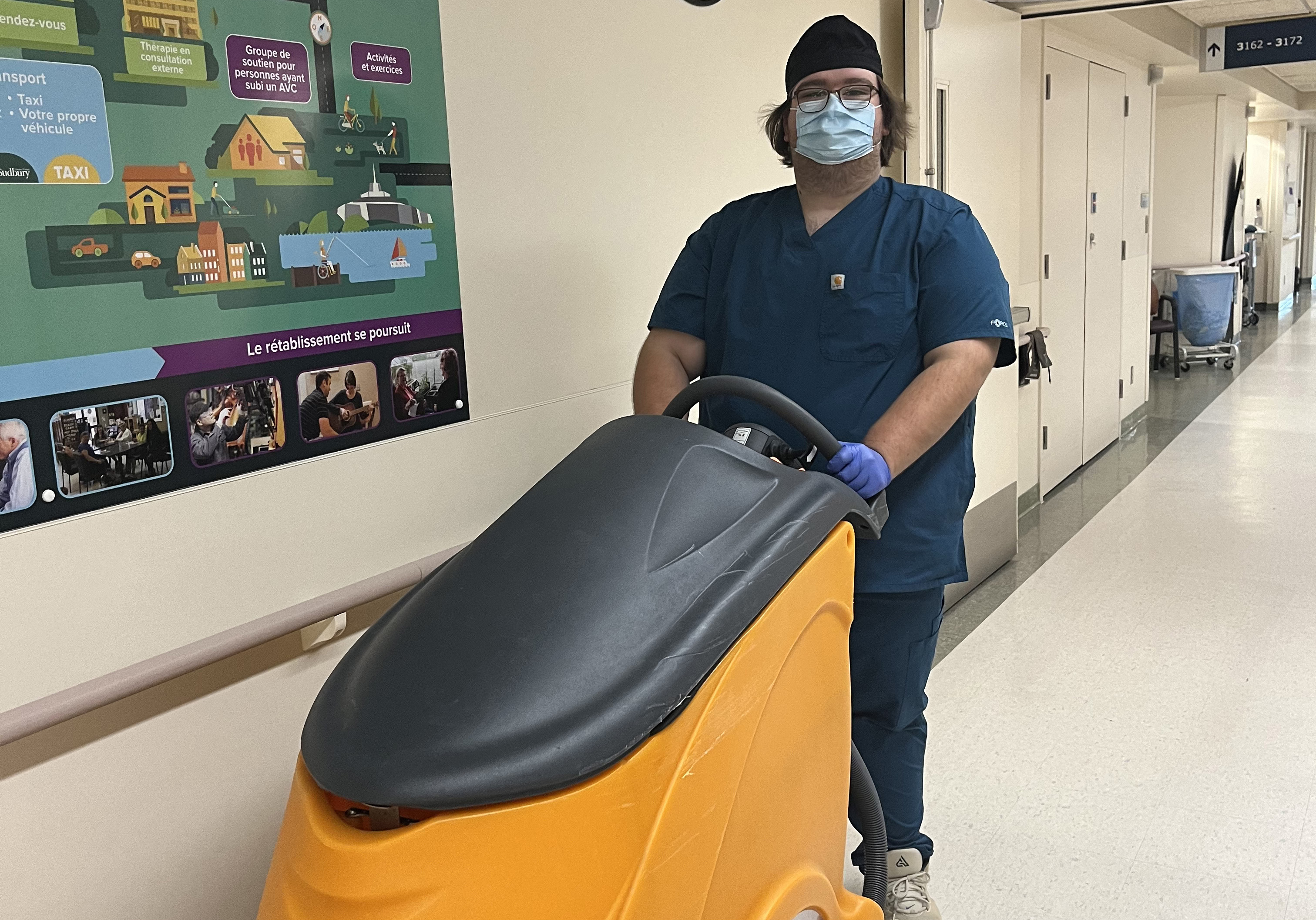 Frank pushing a industrial vacuum through a hallway