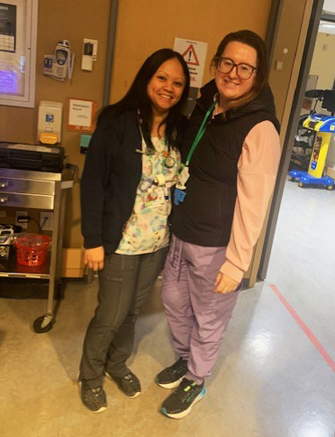 Two women nurses in scrubs smile