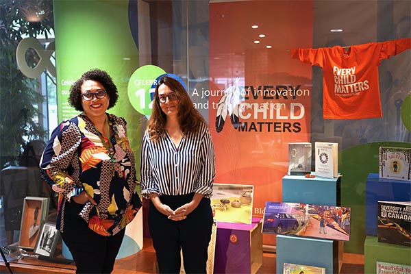 Lorraine Thomas, manager, inclusion, diversity, equity accessibility and anti-racism (IDEAA) and  Iveta Lewis, manager, health sciences library and archives in front of the Truth and Reconciliation display 