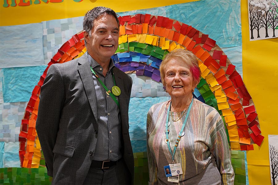 Two adults standing in front a wall with a rainbow
