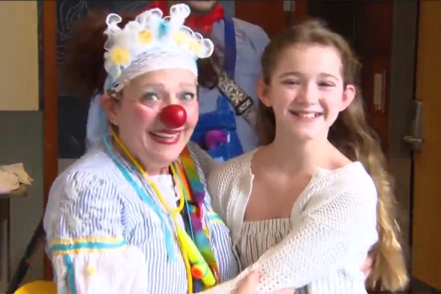 A clown and a child happily walking into a room