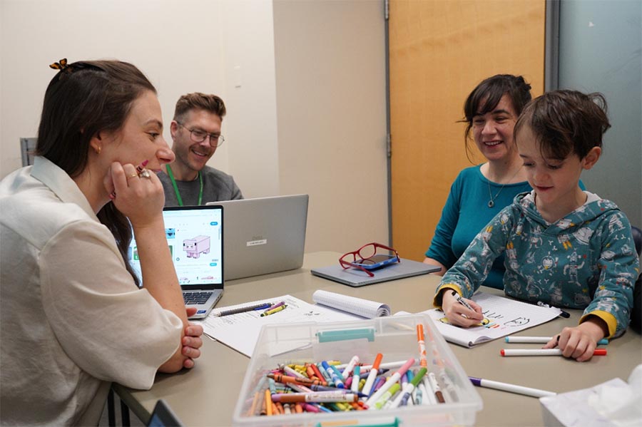 Three adults with a child doing some artworks