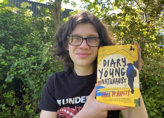 Teen outside holding his new book