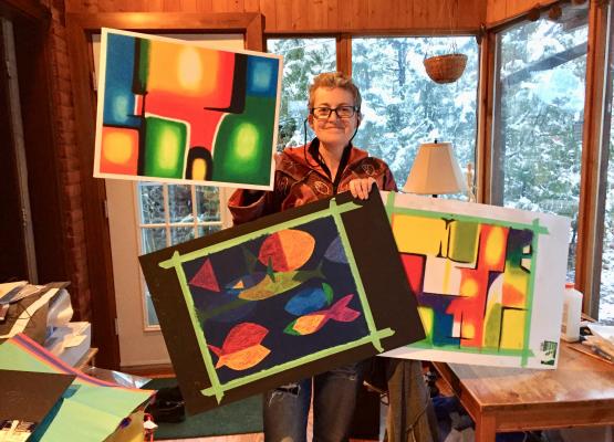 Woman holding bright abstract paintings