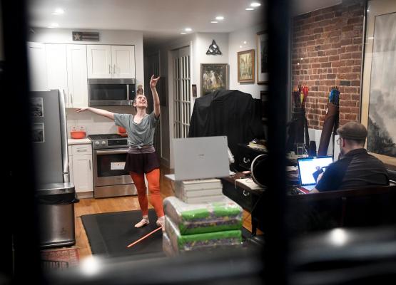Woman doing ballet in kitchen in front of laptop