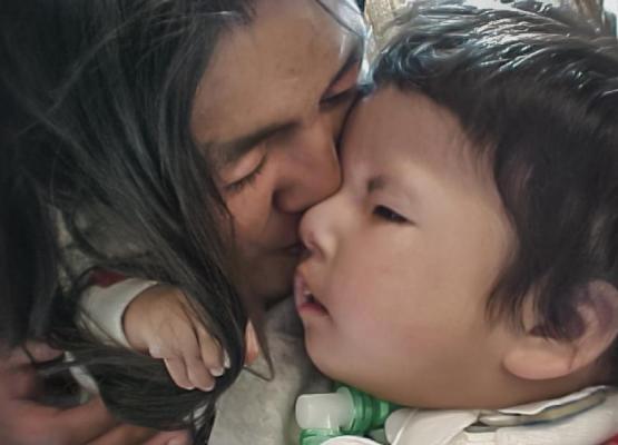 First Nations mother kisses face of toddler son