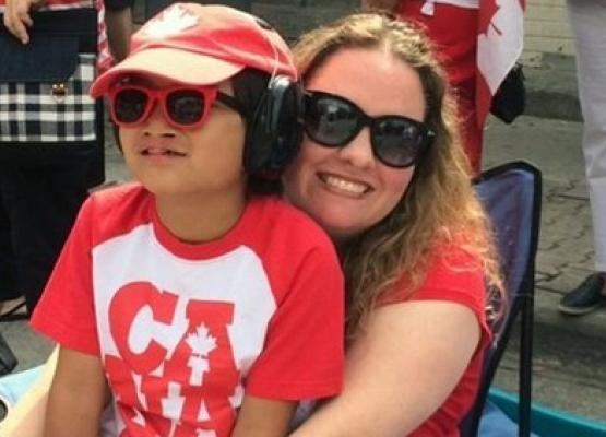Son on mother's lap in Canada Day clothes and sunglasses and smiles