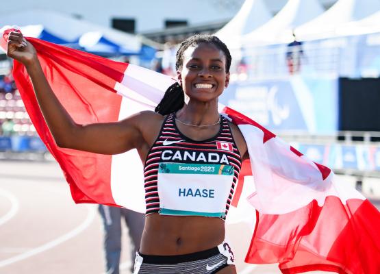 Woman wearing Canada track shirt wrapped in Canadian flag smiles