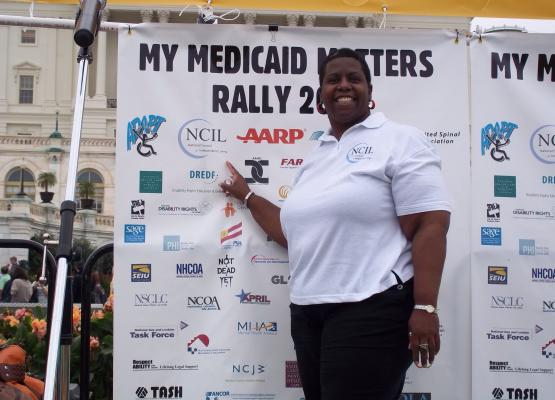 Woman stands in front of large sign that says My Medicaid Matters