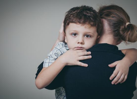 Sad young boy being held by a woman