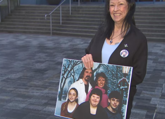 Woman with dark hair holds a large photo of a family