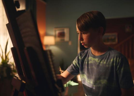 Boy sits at easel drawing