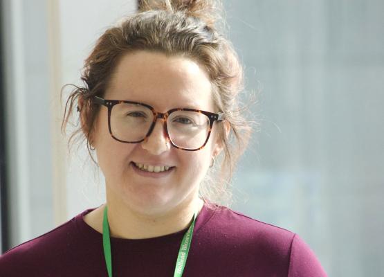 Woman with glasses and brown hair in updo smiles