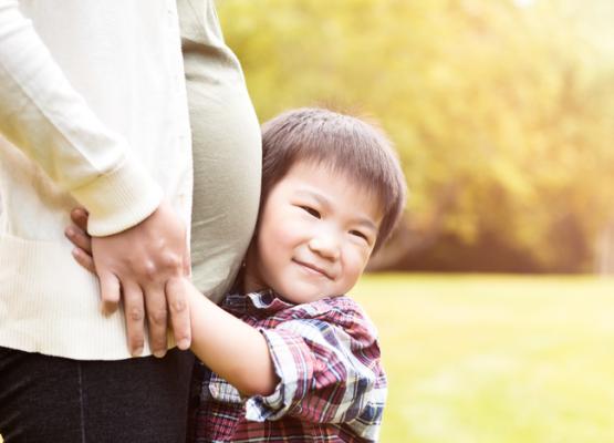 Boy hugs belly of pregnant woman