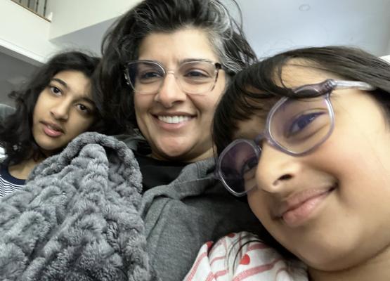 Girl with glasses and woman and teen girl under blankets