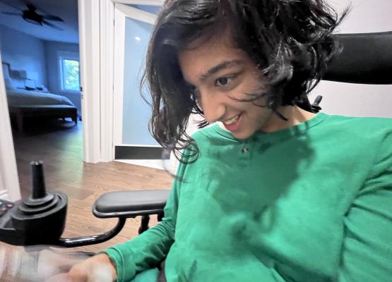 Teen with dark wavy hair and green shirt smiles