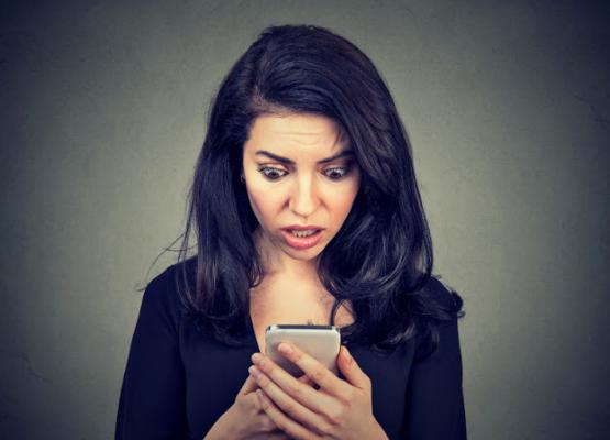 girl looking horrified looking at a cell phone