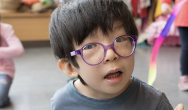 Young boy with glasses and dark hair looking at the camera