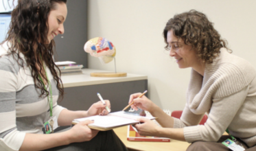 Two women sitting across from each other looking at paperwork