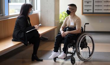Young man in wheelchair talking to staff