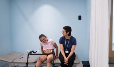 Child laughing with physiotherapist while preparing for a gait assessment