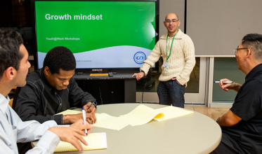 Man presenting, screen reads "Growth mindset", 3 youth around a table
