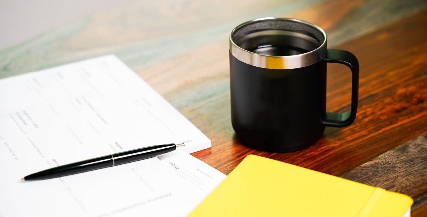 Papers and pen on a desk with mug of coffee