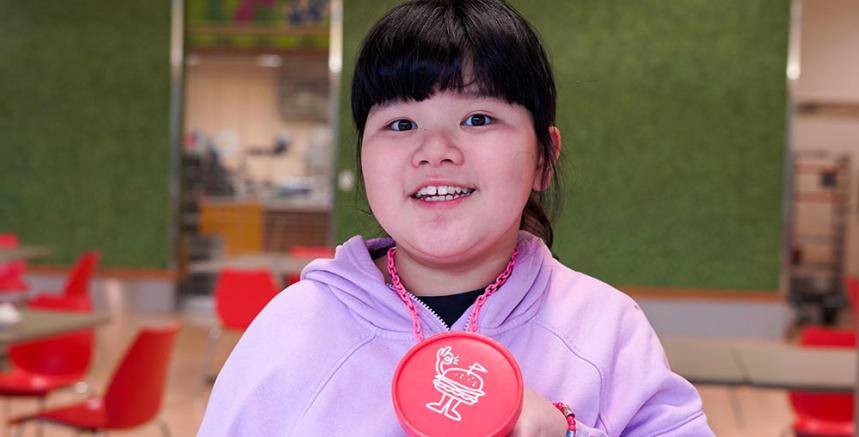 A child is holding a Rosie's Burger badge