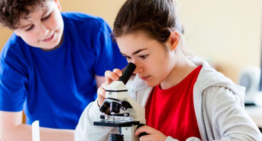 A boy and a girl looking through a microscope