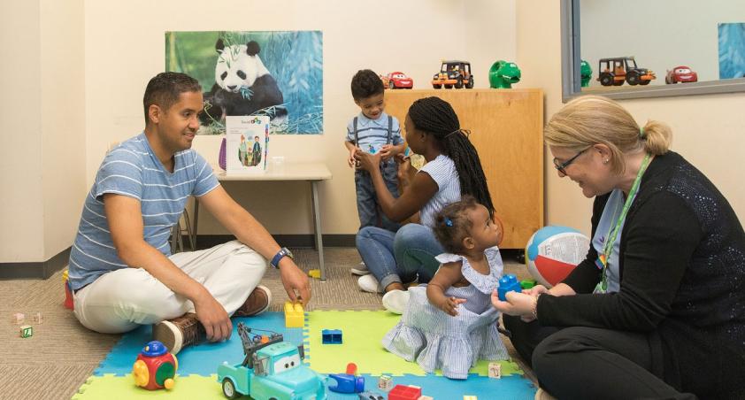 Dr. Jessica Brian consulting with a little patient in a playroom with her parents and brother