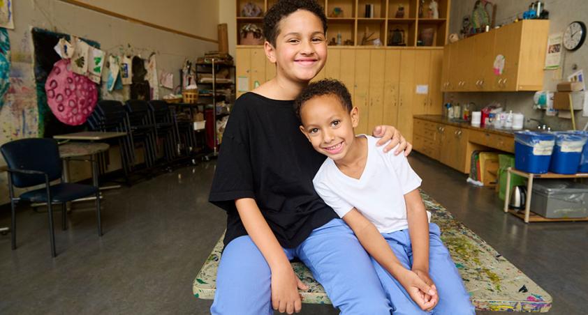 Two siblings sitting side by side in an art studio at Holland Bloorview