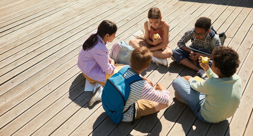 A group of children sitting on a deck to play