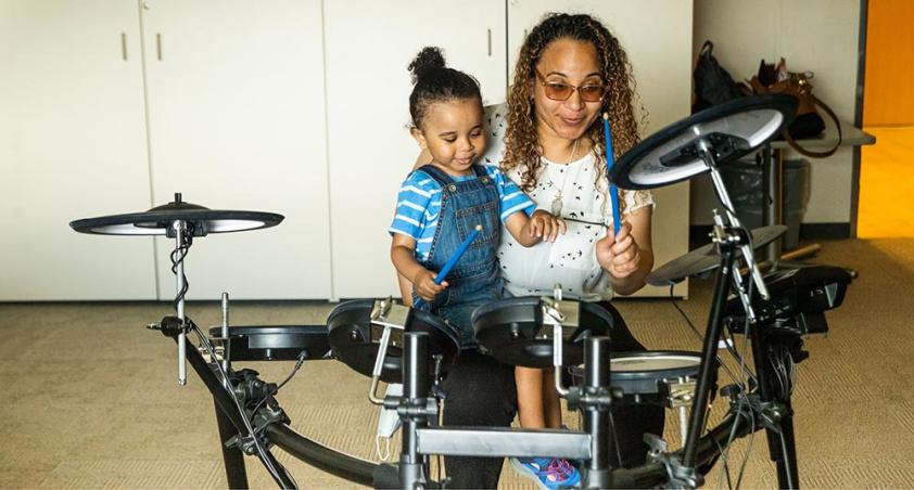 A parent is playing drum with the kid