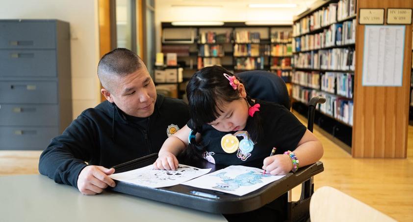 An adult with a child in a library setting