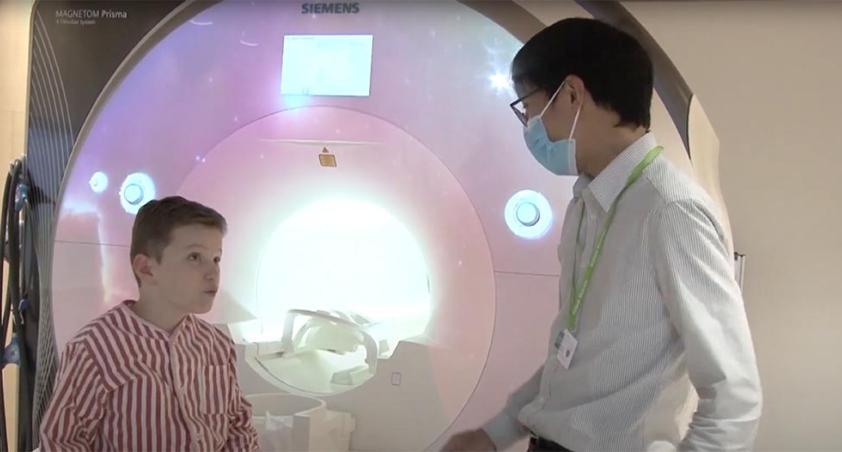 A participant in a MRI research study with the MRI Technician in front os the MRI unit.