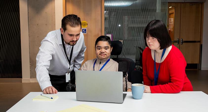 Three people having a meeting, facing a laptop computer