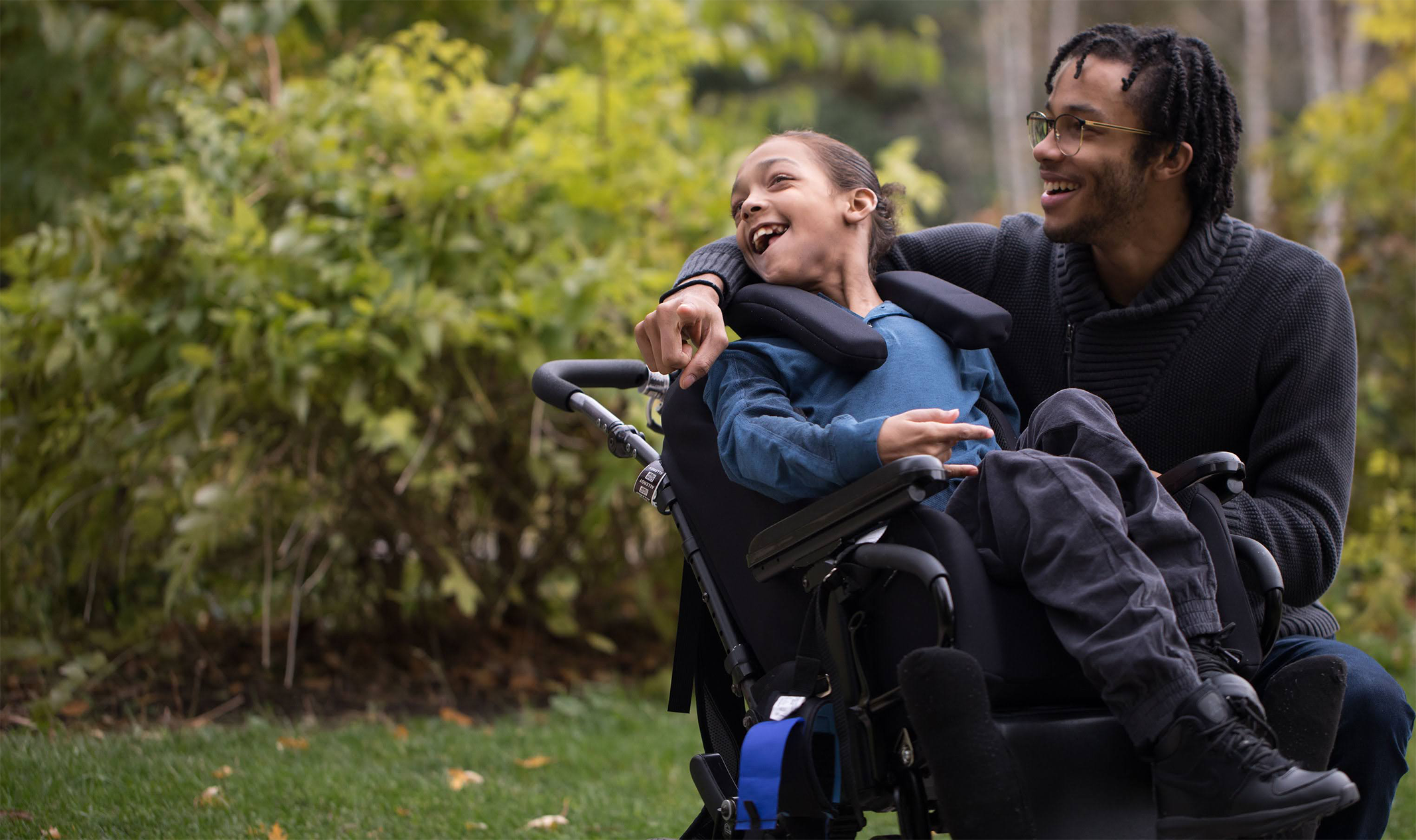 A young girl in a wheelchair and her father has his arm around her