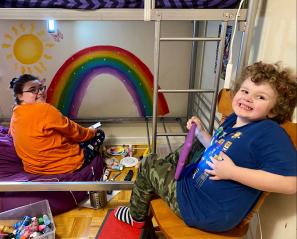 children sitting in front of a painting of a rainbow